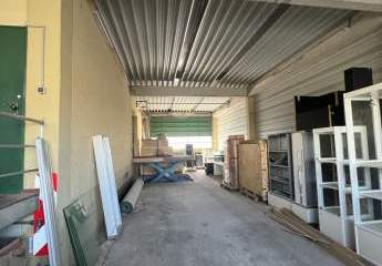 Lagerhalle mit überdachter Ladezone und großem Außenbereich.